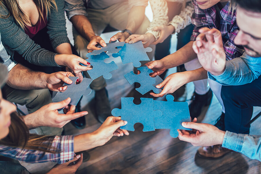 Gesund Führen - Team fügt Teile zu einem Puzzle zusammen - Miteinander - Teamwork - Führungskräfteseminare